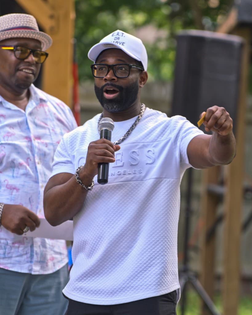 Alonzo Waheed speaking into a microphone at an outdoor event